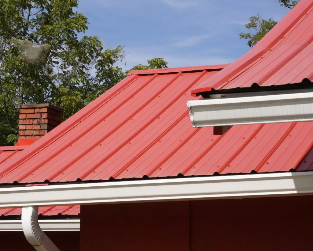 Red Metal panels installed with rain gutters on metal roof.