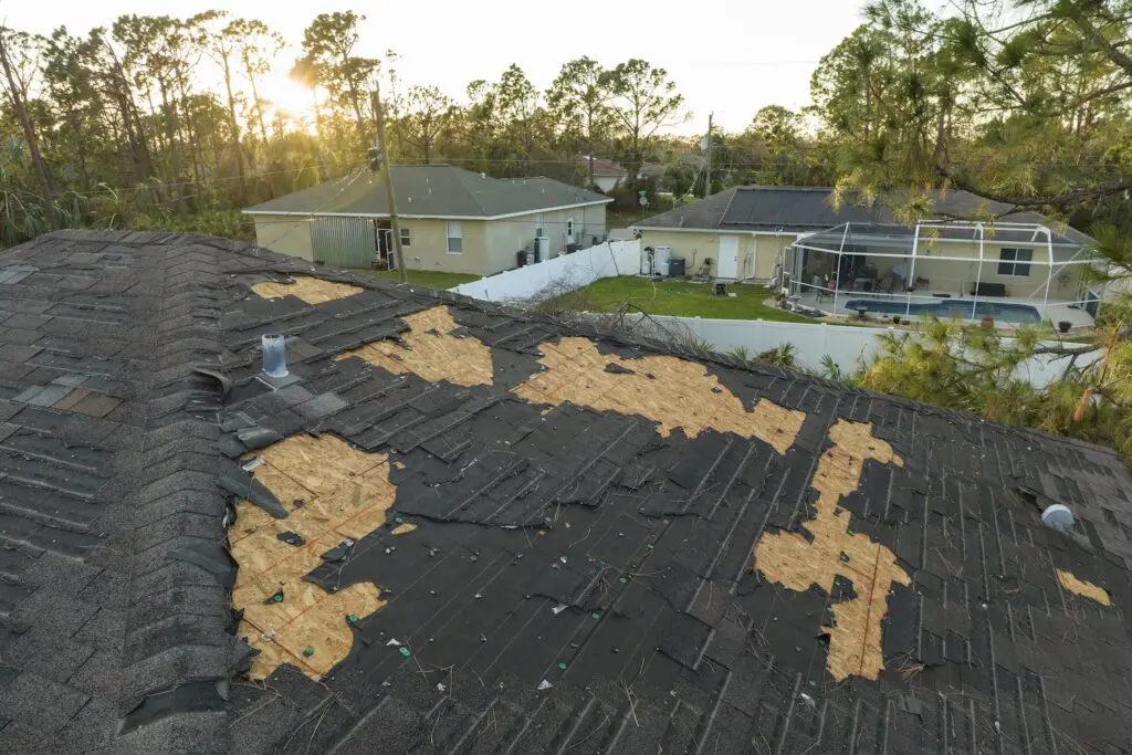 Damaged house roof with missing shingles after hurricane Ian in Florida. Consequences of natural disaster