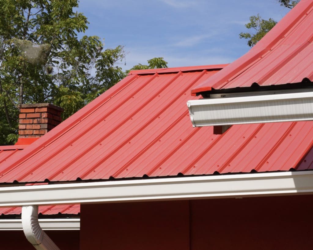 Red Metal panels installed with rain gutters on metal roof.