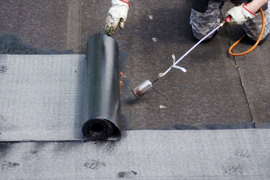 Roofer using blowtorch for commercial flat roof installation
