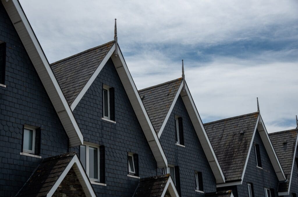Home residential buildings with wooden house roof attics against a cloudy sky