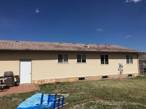 Residential home with light yellow siding and damaged brown roof
