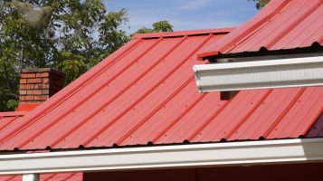 Red Metal panels installed with rain gutters on metal roof.
