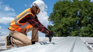 Roofer working on grey metal commercial roof Roofer working on commercial grey metal roof.