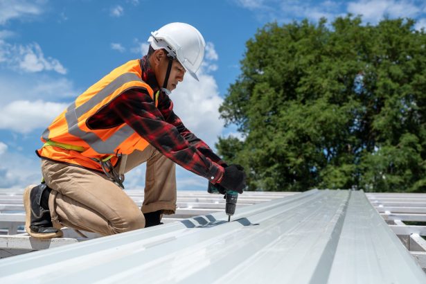 Roofer working on grey metal commercial roof Roofer working on commercial grey metal roof.